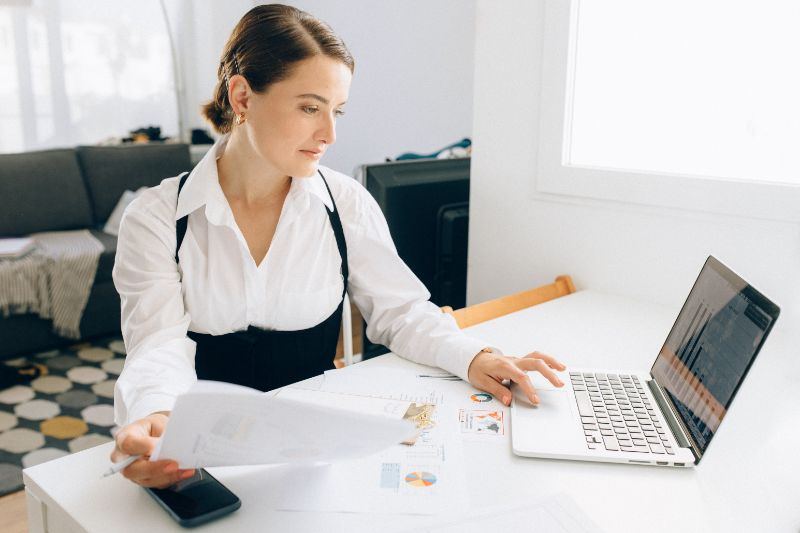 a woman holding a paperwork and with a laptop