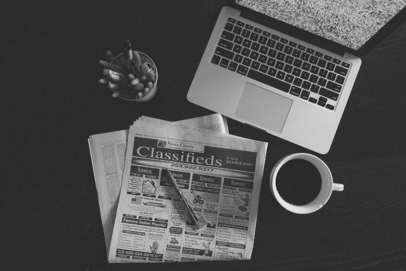 A black and white photo of a laptop and a newspaper