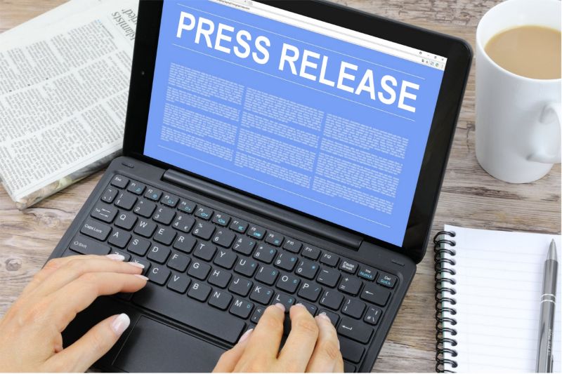 Typing on a laptop with press release content