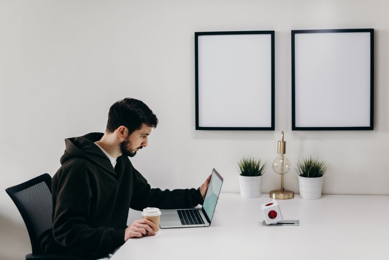 a guy on his laptop while holding a coffee