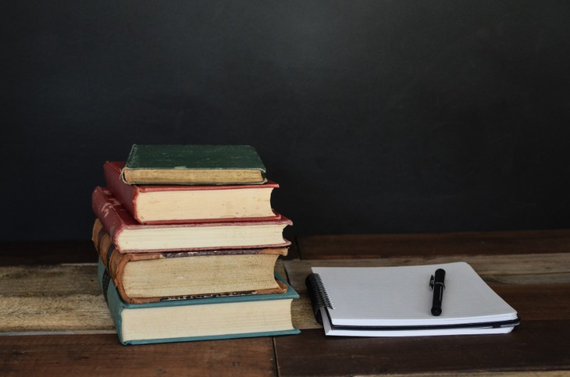 Books stacked, notebook with a pen on it