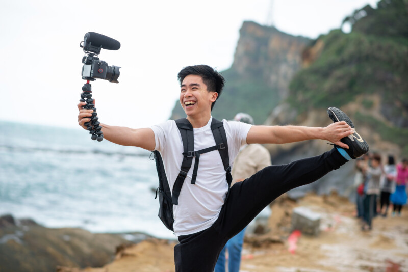 A vlogger holding a camera smiling