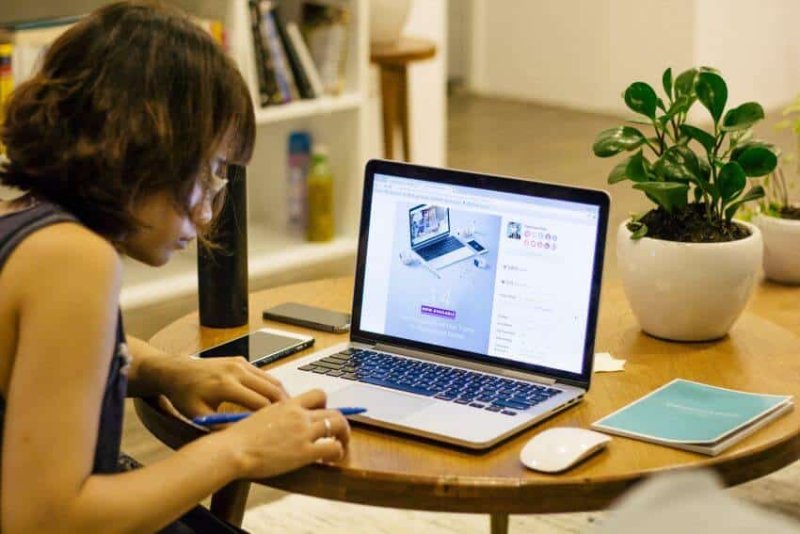 a woman working on her laptop with pen and paper