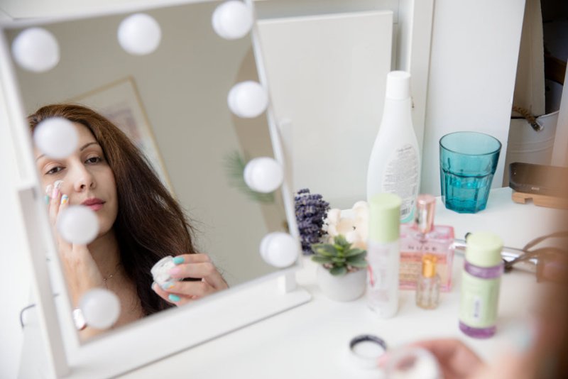 a lady looking at the mirror while using her face cream