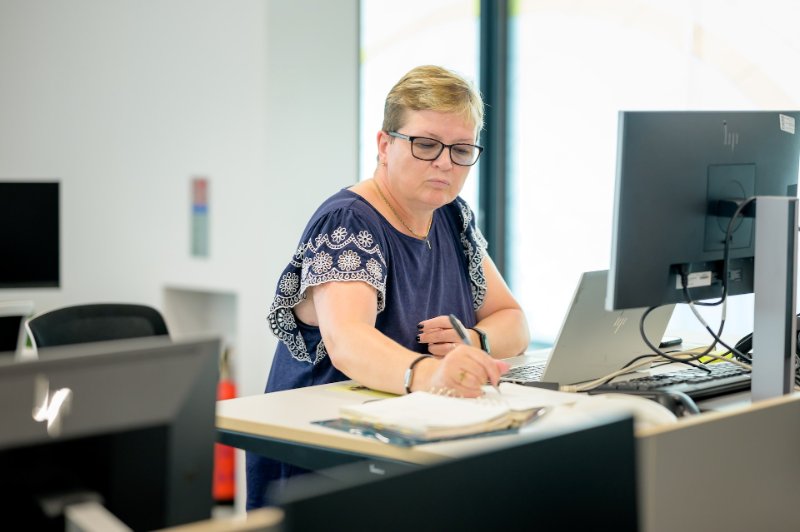 Lady taking notes while sitting at desk and using devices