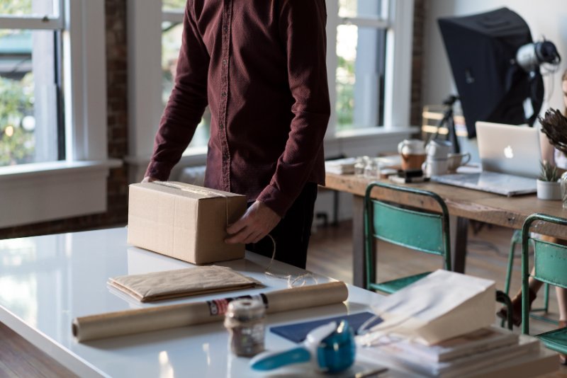 a person packing a box on the table with other packing items