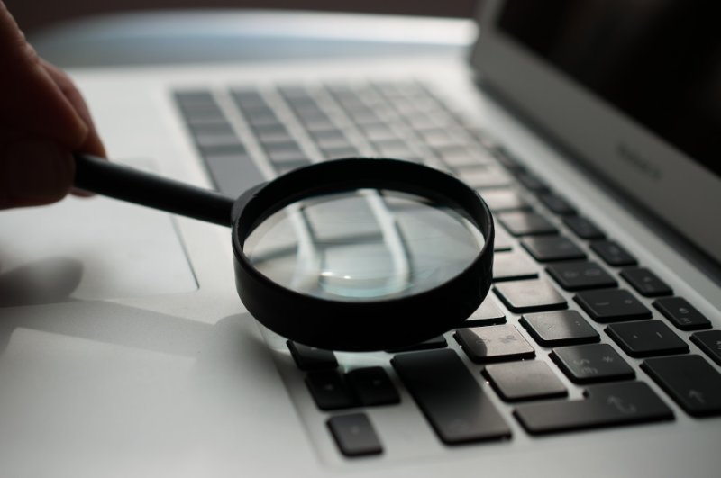 a person using the glass magnifier over the laptop keyboard