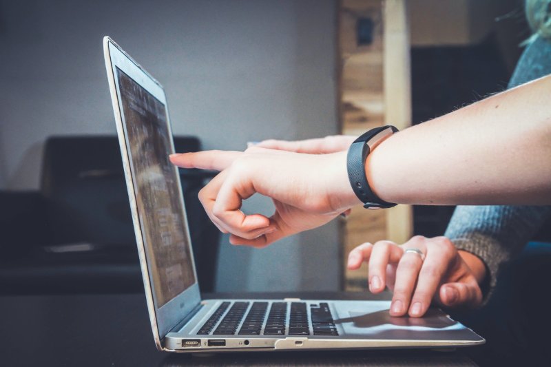 Two people discussing something while pointing at laptop screen