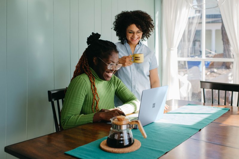 two women watching something on the laptop and smiling