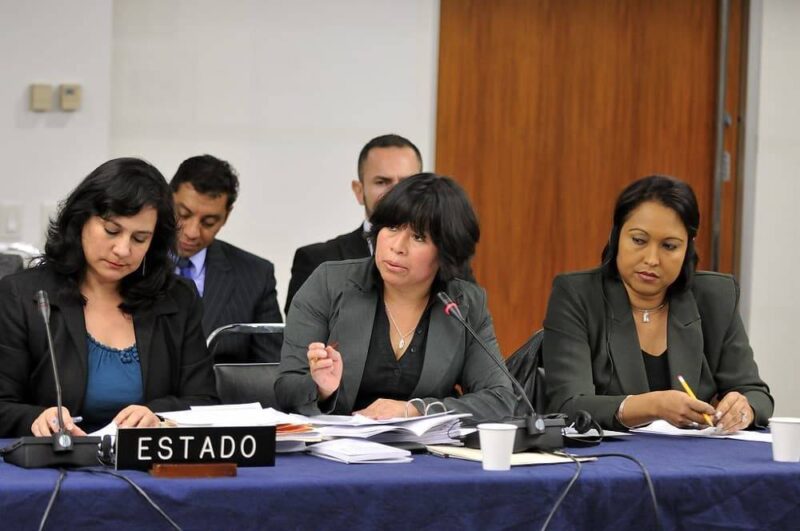 people seated on chairs in a court room and presenting