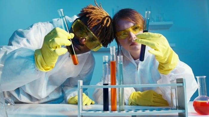 forensic experts wearing lab attire and looking at the test tubes