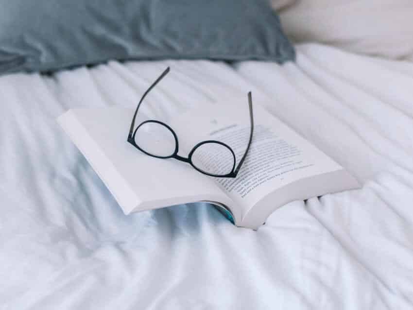 Book and glasses on a bed