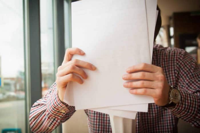 man covering his face with papers