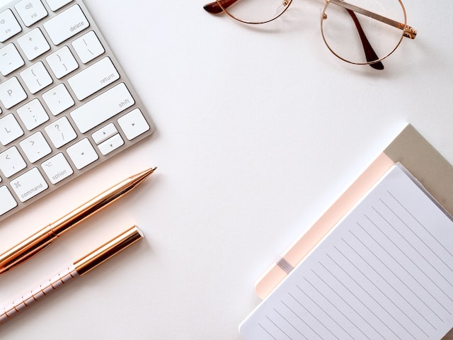 Working desk with keyboard, pen, sunglasses, and notepad