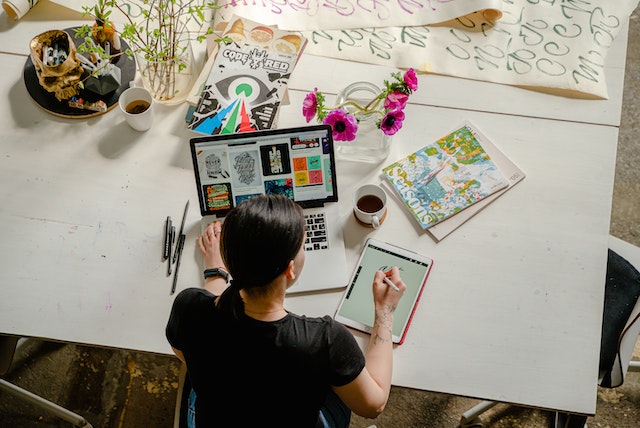 Lady sitting at her desk using laptop and iPad