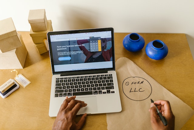 A man working on laptop with a pen in his right hand