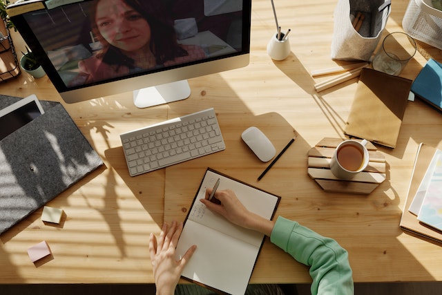 Woman sitting at a desk, watching a video and taking notes