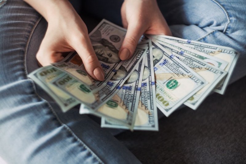 a person's hands holding dollars bills