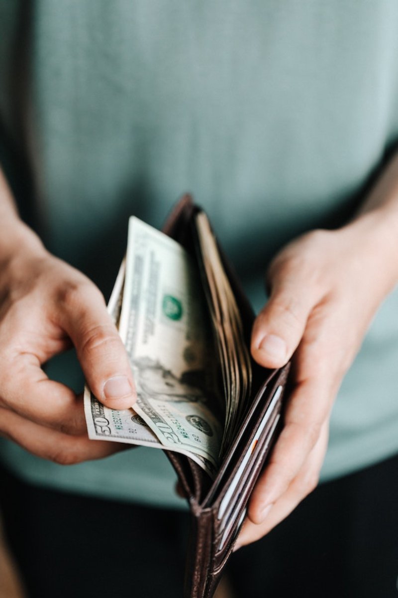 hands holding a wallet with dollar bills