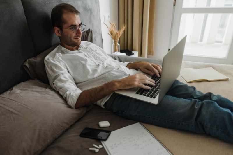 A man on a bed with his laptop