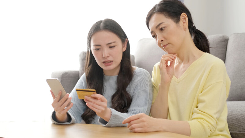 Worried mother and daughters holding a credit card