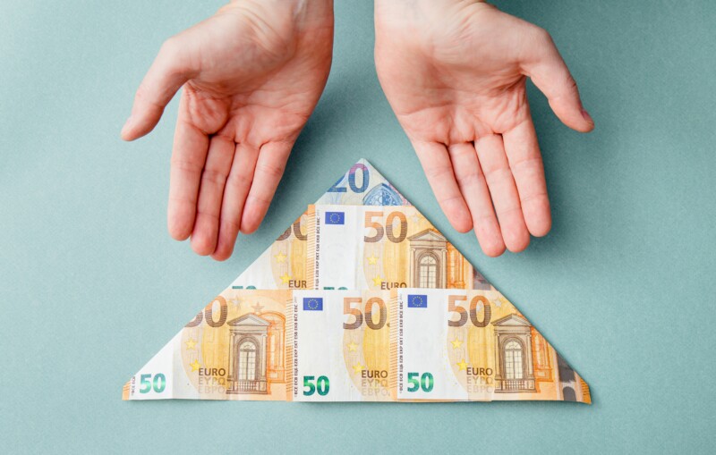 Hands showing a set of paper bills shaped into a triangle