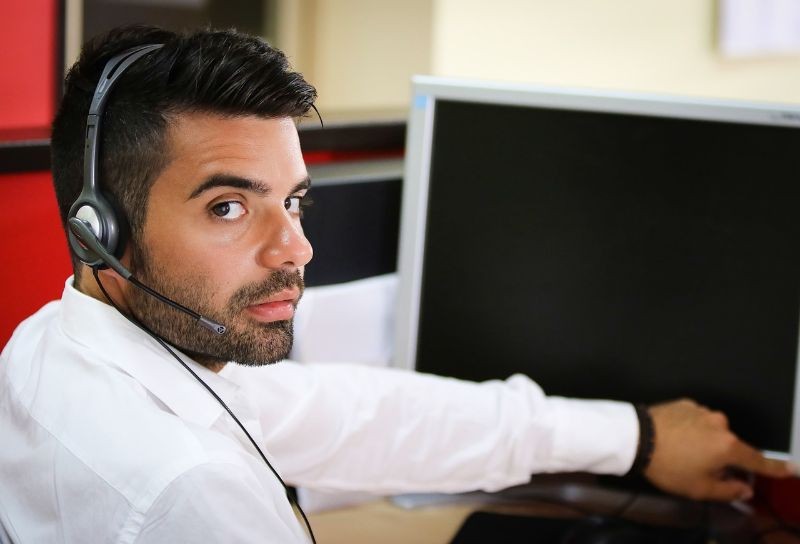 Male customer service representative facing a computer screen