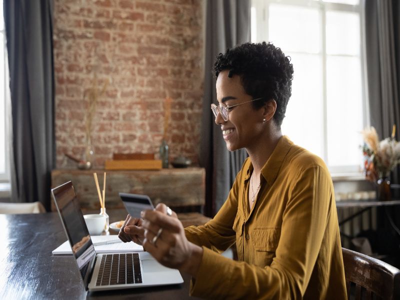 Happy young African customer woman using laptop and credit card