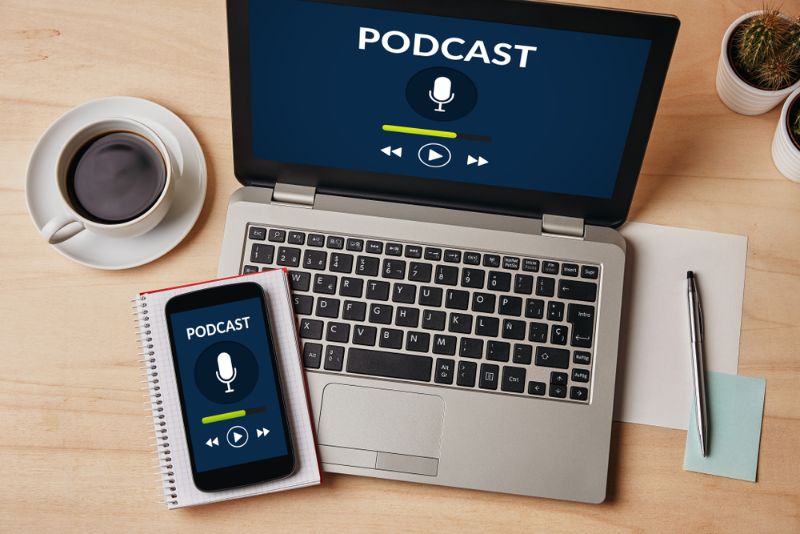 Podcast concept on laptop and smartphone screen over wooden table