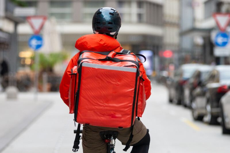 Unrecognizable courier on bicycle delivering food in City