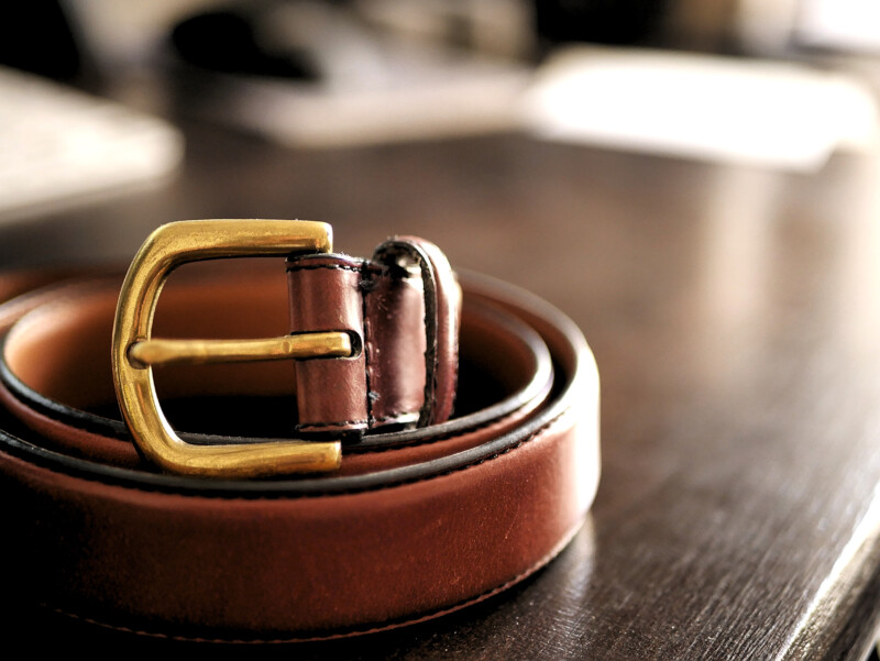 Brown Leather Belt on Dark Wooden Desk