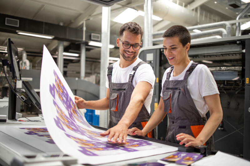 Graphic engineers or workers checking imprint quality in modern print shop