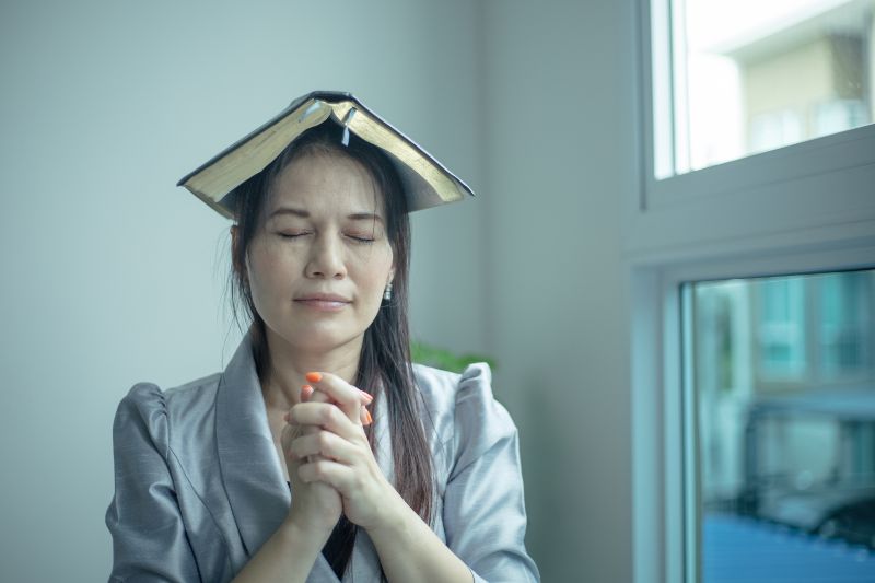 Woman praying and putting bible on her head