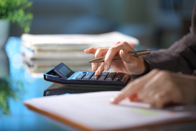 Executive hands calculating using calculator in the night at office