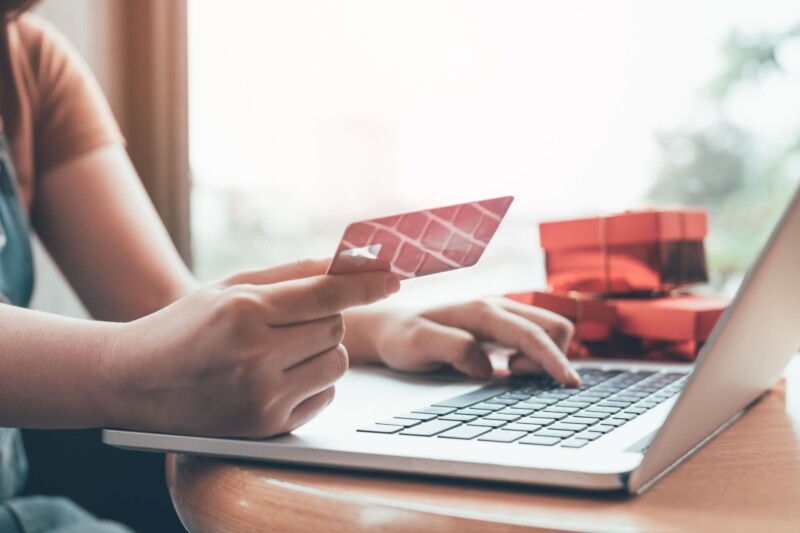 Close up woman hand holding credit card and typing laptop keyboard