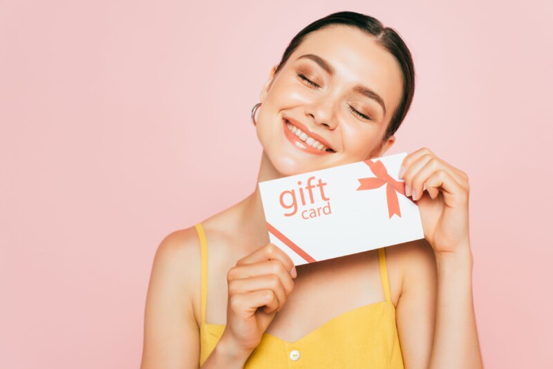 Young woman with closed eyes holding gift card