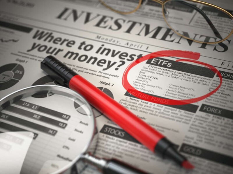 Investmets newspaper with loupe and marker highlighting ETF