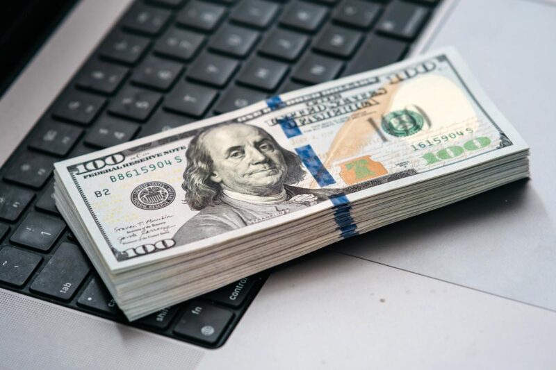 Stack of US dollars on keyboard depicting online earnings, finance, and digital economy.