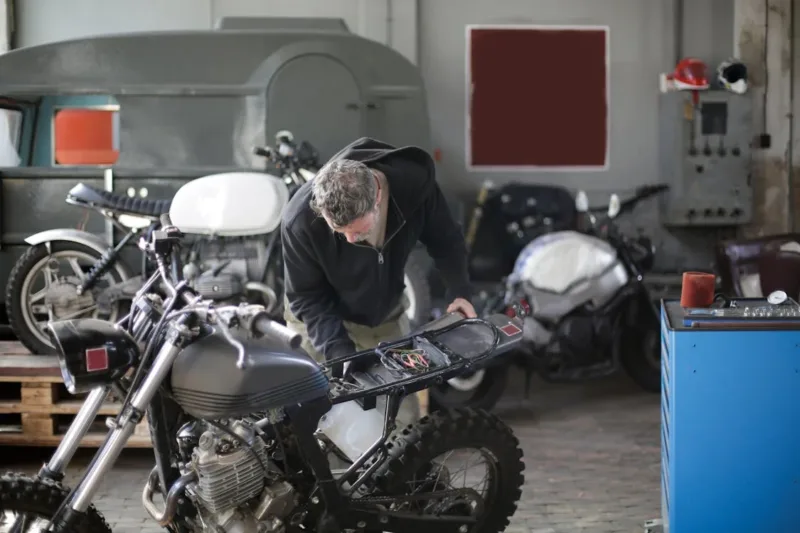 An adult male mechanic fixing motorbike in garage