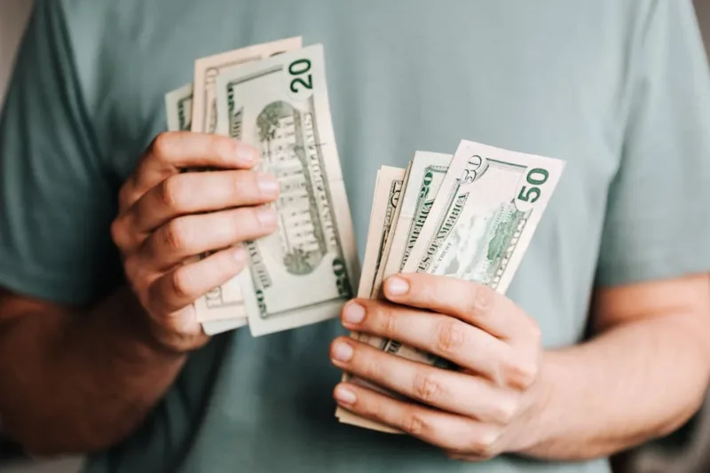 Crop man counting dollar banknotes
