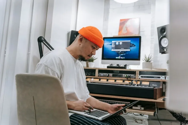 Man in White Shirt and Orange Hat Using Laptop