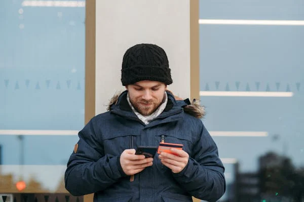 Cheerful man transferring money on his mobile device.