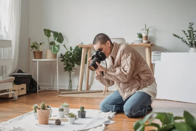 A Woman in a Beige Jacket Taking a Photo of Succulents